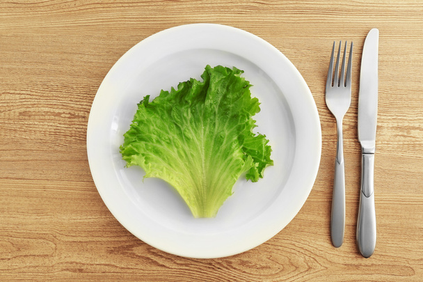 Fehér tányér saláta levél, fából készült háttér - Fotó, kép