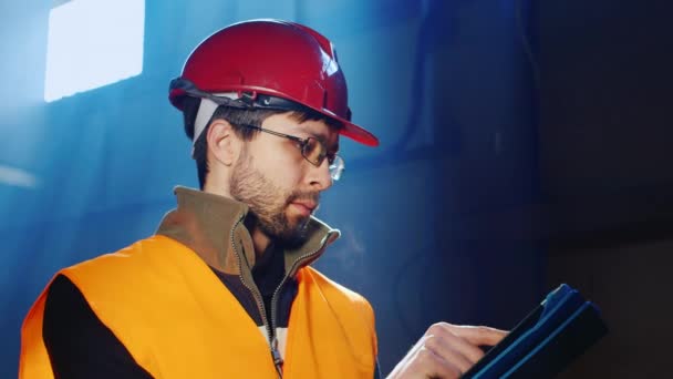 Worker in overalls and a helmet uses a tablet - Metraje, vídeo