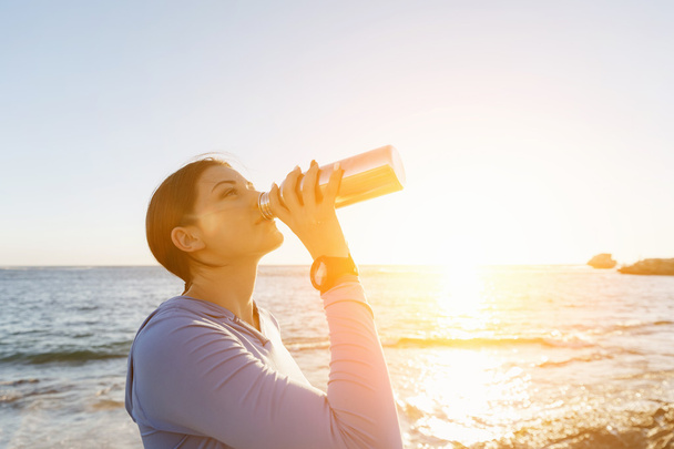 Woman drinking water on beach - Foto, Imagen