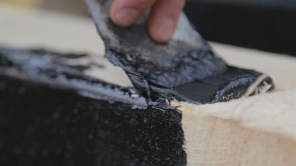 Liquid bitumen is applied to the wood beam. The process of applying liquid bitumen. - Materiał filmowy, wideo