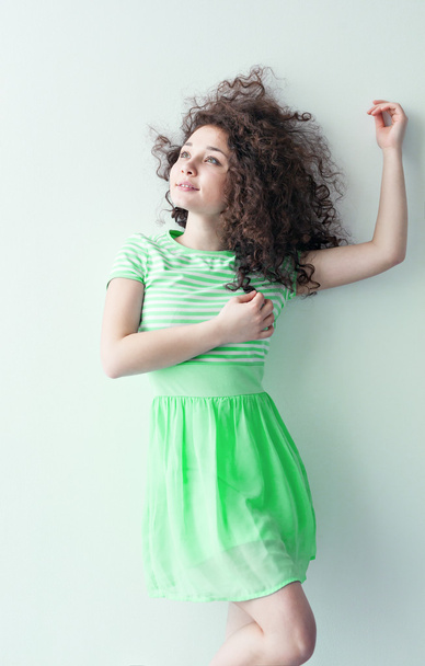 Молода дівчина кавказької зовнішності танцює і мріє про яскраву кімнату на літній день. Хвилясті Кучеряве волосся і зелене плаття. Відпочинок і бути щасливим. - Фото, зображення