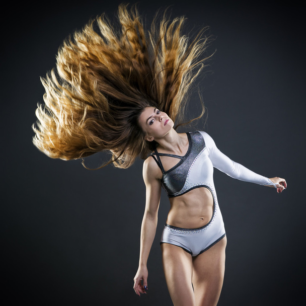 Beautiful young woman with flowing hair in studio - 写真・画像