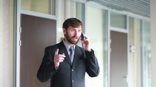 successful business man having cell telephone conversation while standing in office interior, - Video, Çekim