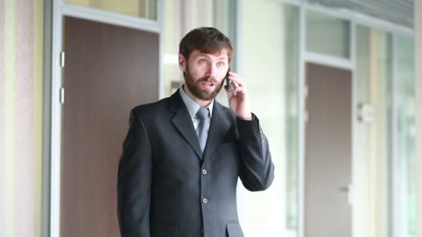 successful business man having cell telephone conversation while standing in office interior, - Filmmaterial, Video