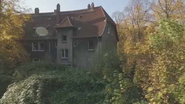 Luftaufnahme eines verlassenen Viertels in der Zechenstadt Gladbeck, Deutschland, Tiefflug, mittlere Kamerafahrt von rechts nach links vor einem schäbigen Haus und einem riesigen Baum mit gelbem Herbstlaub. - Filmmaterial, Video