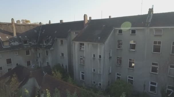 Almanya'nın Gladbeck kentinde terk edilmiş bir mahallenin havadan, mercek parlamasıyla soldan sağa doğru yavaşça kaydırılan eski bir evlerin önünde sağdan sola orta izleme çekimi. - Video, Çekim
