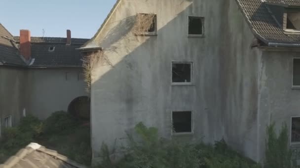 Almanya'nın Gladbeck kentinde terk edilmiş bir mahallenin havadan, sağdan sola doğru, eski bir evlerin önünden sola doğru orta izleme atışı, sonra yavaşça çatı ve baca üzerinde soldan sağa bir panning atış ile yükseliyor. - Video, Çekim