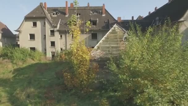 Aerial of an abandoned quarter in the coal-mining town Gladbeck, Germany, low altitude flight, close tracking shot from left to right in front of a shabby row of houses and coppice. - Footage, Video