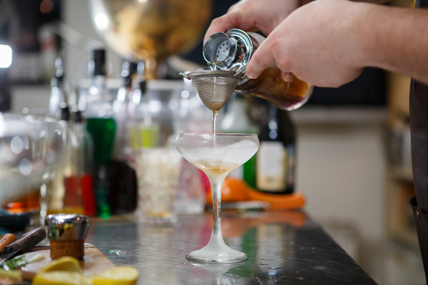 Bartender coocks cocktail behind a bar counter - 写真・画像