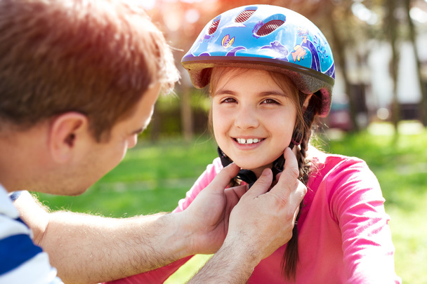 Vater lehrt mutige Tochter Fahrradfahren und setzt Schutzhelm auf - Foto, Bild