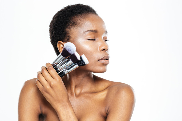 Afro american woman with closed eyes holding makeup brushes - Foto, Bild