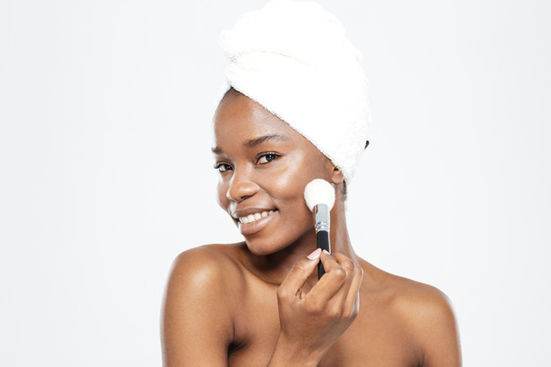 Afro american woman applying makeup with brush - Fotó, kép