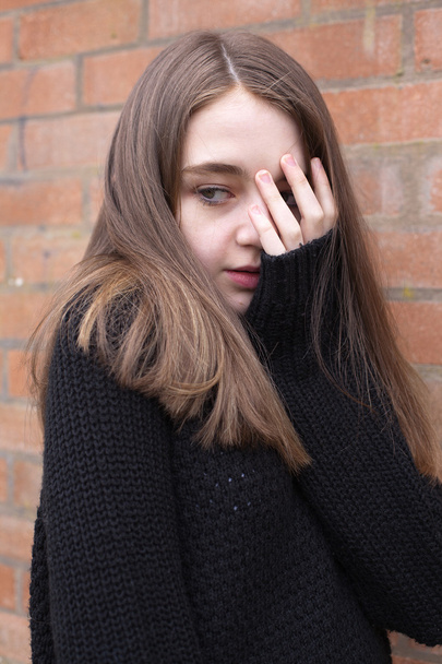 Young girl with her hand covering her face looking frightened  - Фото, изображение