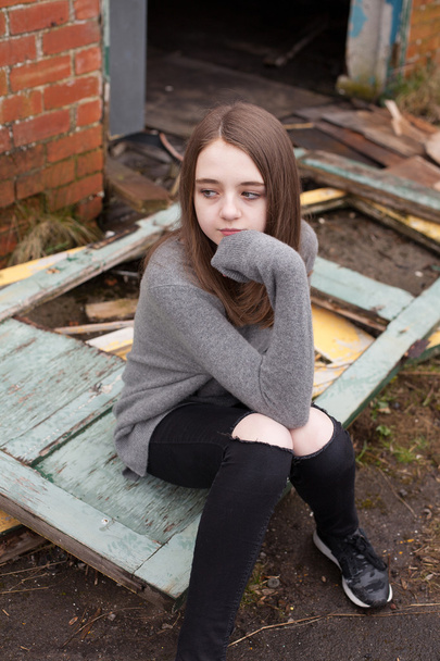 Pretty young teenage girl sitting on some old doors  - Photo, Image