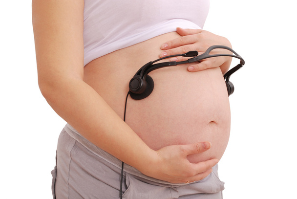 Pregnant woman with headphones on her stomach - Photo, Image