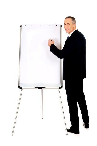 Male executive writing on a flipchart - Фото, зображення