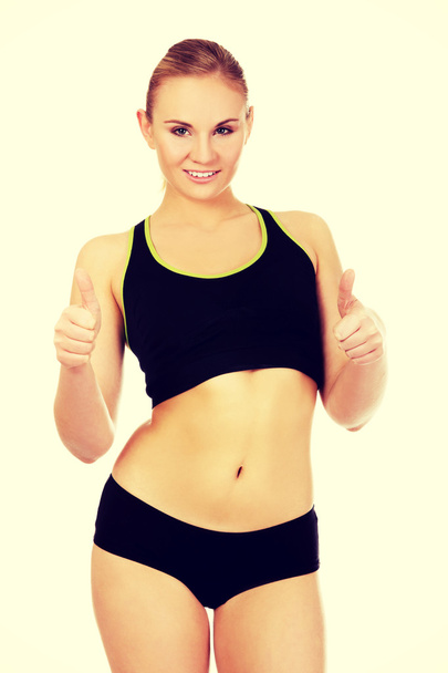 Young athletic woman showing thumbs up - Foto, afbeelding