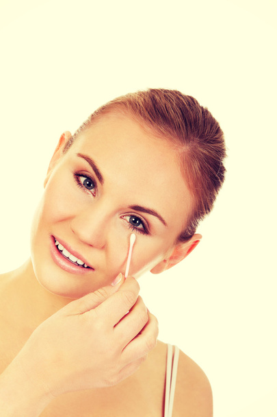 Young woman removing eye makeup with cotton swab - Foto, immagini