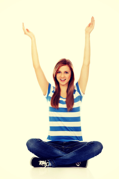 Happy teenage woman sitting with arms up - Foto, Imagen