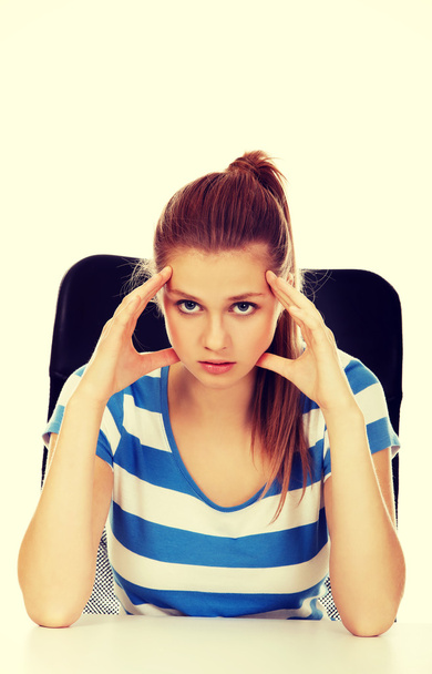 Worried teenage woman sitting behind desk - Φωτογραφία, εικόνα