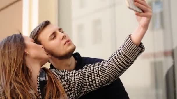 Güzel çekici gülümseyen kadın yakışıklı erkek arkadaşı ile onun telefonunda selfies alarak. - Video, Çekim