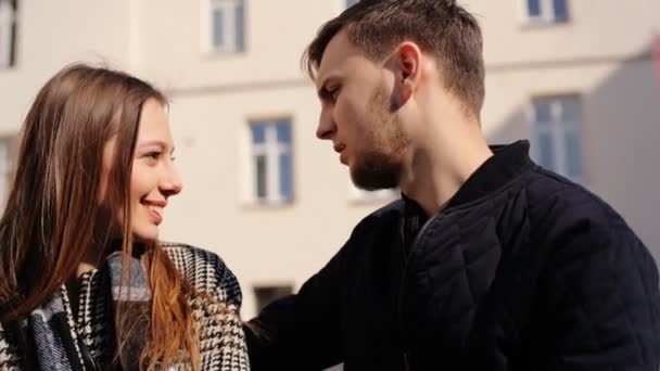 Twee jonge geliefden praten met elkaars zittend op een bankje op de straat. - Video