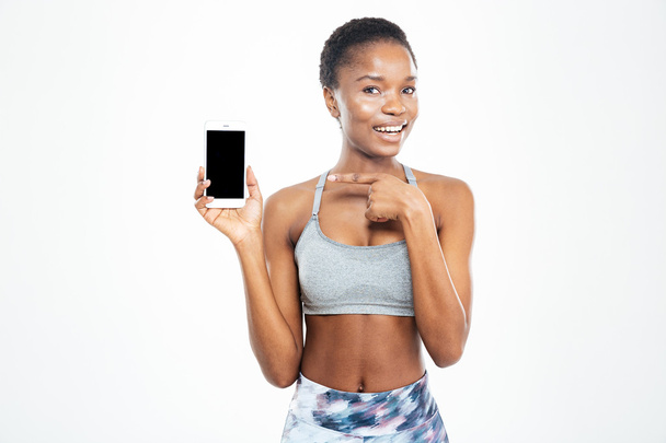 Cheerful pretty young african american sportswoman holding blank screen smartphone  - Fotó, kép