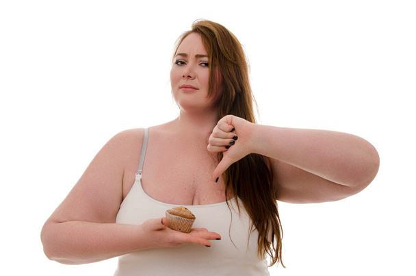 Μια λίπος γυναίκα με ένα μάφιν στο χέρι της να απομονωθεί σε λευκό φόντο - Φωτογραφία, εικόνα