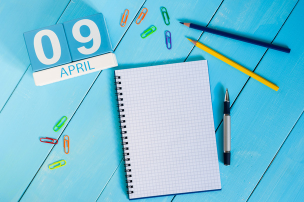 9 kwietnia. Zdjęcie z 9 kwietnia drewniany kalendarz kolorów na niebieskim tle. Dzień wiosny, pusta przestrzeń dla tekstu - Zdjęcie, obraz