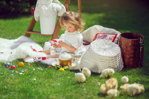 Child sits on a meadow around Easter decoration - Foto, afbeelding