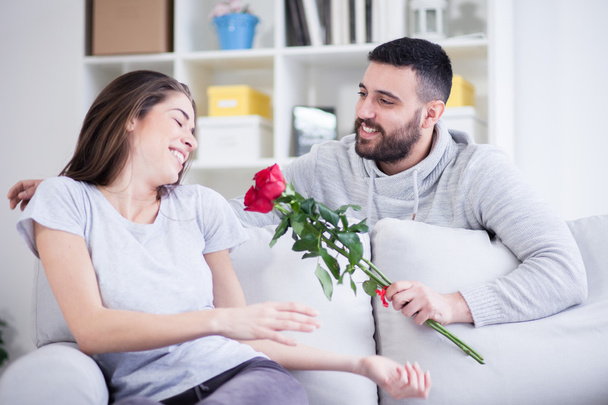 Junger Mann schenkt seiner Freundin eine rote Rose - Foto, Bild
