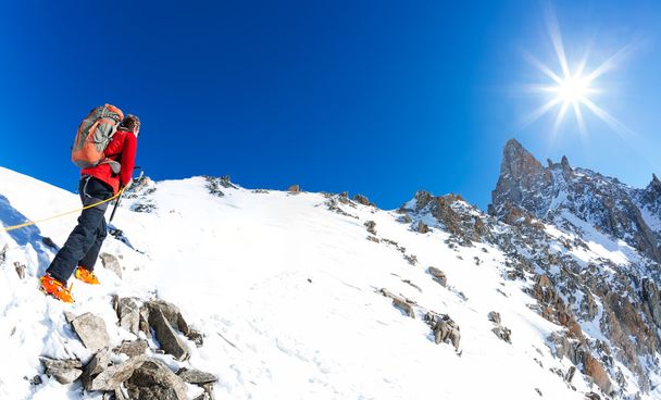 L'alpiniste grimpe un pic enneigé. En arrière-plan le célèbre pic de la Dent du Geant dans le massif du Mont Blanc, la plus haute montagne européenne. Alpes, Chamonix, France, Europe
. - Photo, image