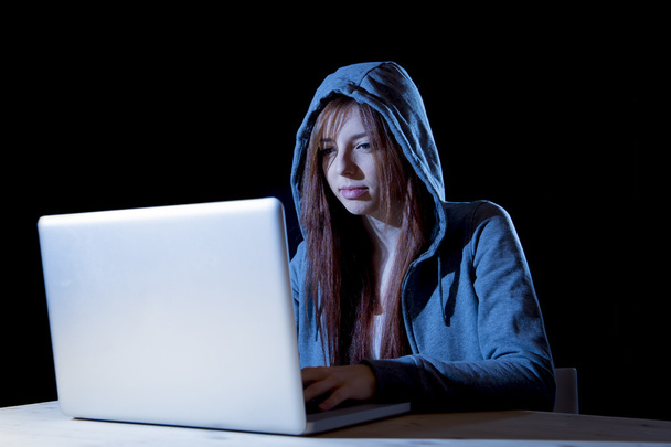 fiatal vonzó tini nő visel hood szaggató köhögés a laptop számítógép számítógépes bűnözés cyber bűnözés fogalma - Fotó, kép