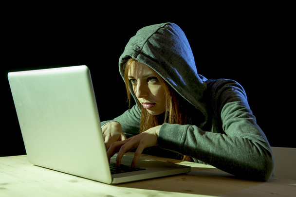 joven atractiva mujer adolescente con capucha en la piratería informática portátil cibercrimen concepto de delito cibernético
 - Foto, imagen