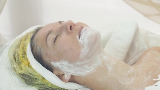 Aikuinen nainen kasvot joitakin savi valkoinen naamio kauneushoitola. Kosmeettinen menettely
 - Materiaali, video