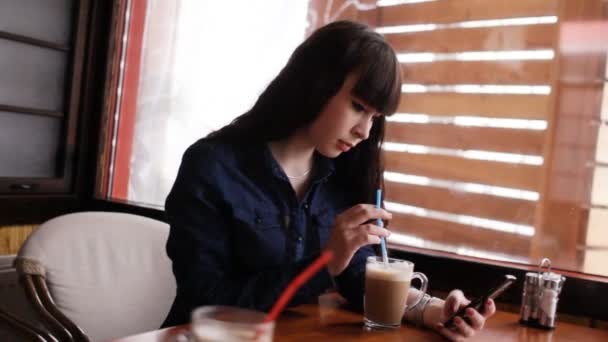 Jong meisje met behulp van smartphone in het café. Handheld. - Video