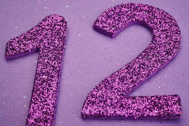 Número doze cor roxa sobre um fundo roxo. Aniversário
 - Foto, Imagem