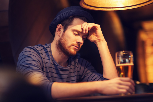 unhappy lonely man drinking beer at bar or pub - Foto, afbeelding