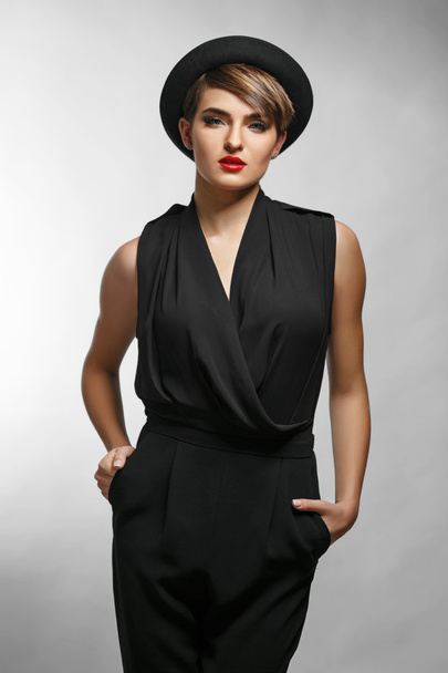 Retrato de una mujer de negocios elegante con ropa negra y un sombrero de moda
. - Foto, imagen