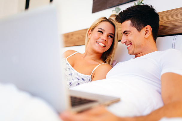 Couple with laptop in bed reading news - Φωτογραφία, εικόνα
