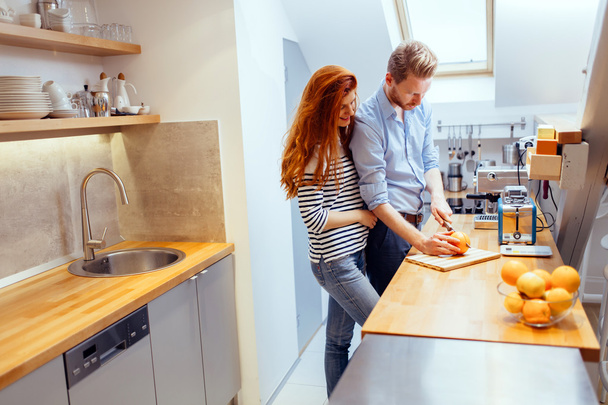 Couple making orange smoothie in kitchen - Фото, изображение