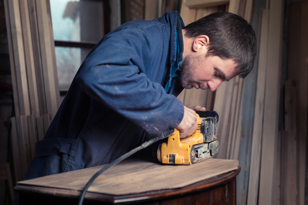Mobília de restauração de carpinteiro com lixadeira de cinto
 - Foto, Imagem