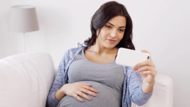 pregnant woman taking selfy by smartphone at home - Materiał filmowy, wideo