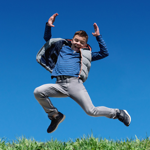 Happy teen boy jumping on meadow - Photo, Image