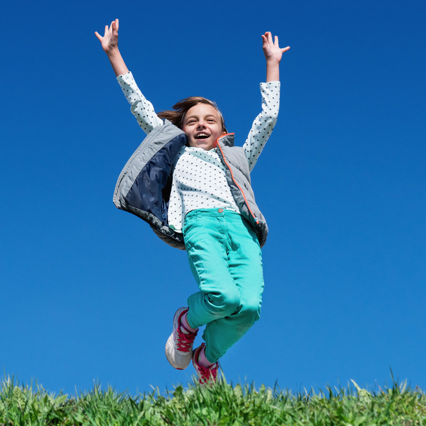 Happy little girl jumping on meadow - 写真・画像