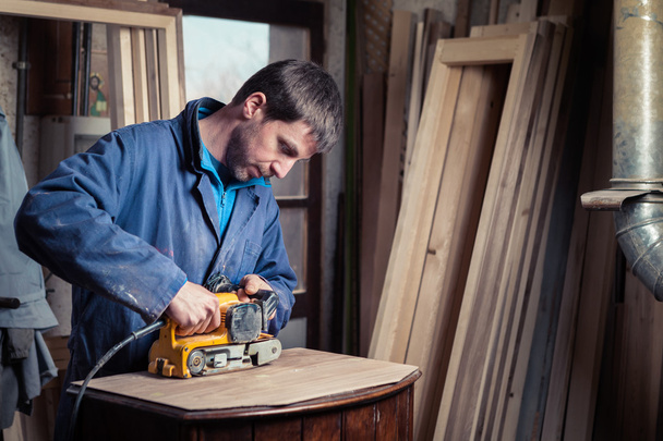 Carpenter restoring furniture with belt sander - Photo, Image