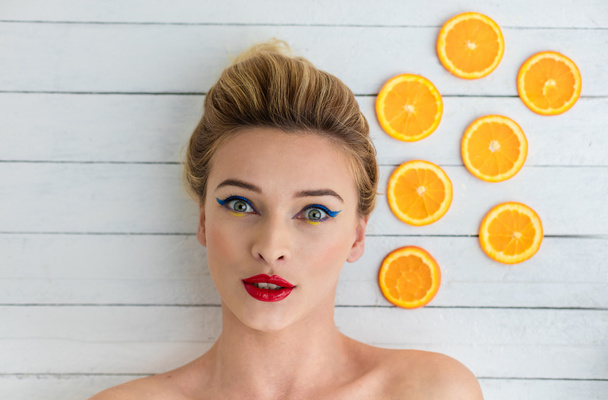 blonde woman laying next to slices of orange - Foto, immagini