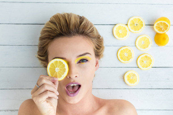 blonde woman laying next to slices of lemon - Foto, imagen