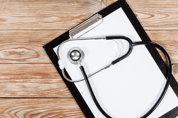 Medical clipboard and stethoscope on wooden table background. - Photo, Image
