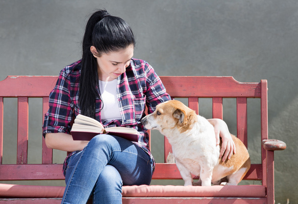 Girl with dog reading a book - Valokuva, kuva